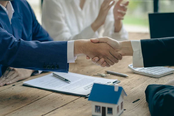 A home agent shakes hands with a customer after signing a contract to buy a home or rent it in the real estate agent\'s office.