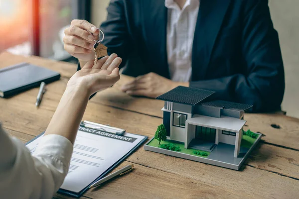 Sales representatives hand out the house keys to customers after signing a contract to buy a house or rent a new home on the table. concept of buying a house