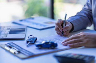 Araba kiralama konsepti, masada oyuncak arabalarla çalışan Asyalı iş kadını. Araba, mülk, mülkiyet, sigorta ve ulaşım kavramları.