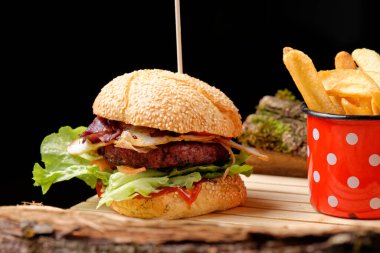 Gurme taze Amerikan hamburgeri ve ahşap masada patates kızartması.