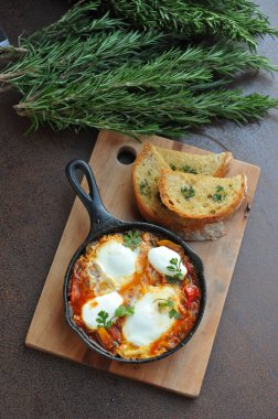 Bir kase sahanda yumurta, pastırma ve siyah ekmekli vişneli domates. 