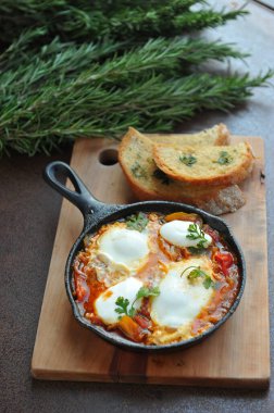 Bir kase sahanda yumurta, pastırma ve siyah ekmekli vişneli domates. 