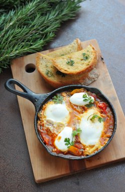 Bir kase sahanda yumurta, pastırma ve siyah ekmekli vişneli domates. 