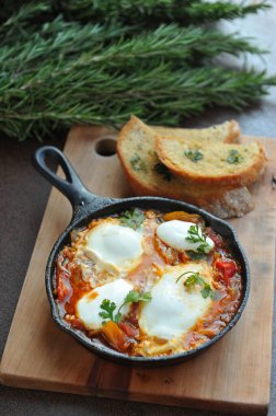 Bir kase sahanda yumurta, pastırma ve siyah ekmekli vişneli domates. 