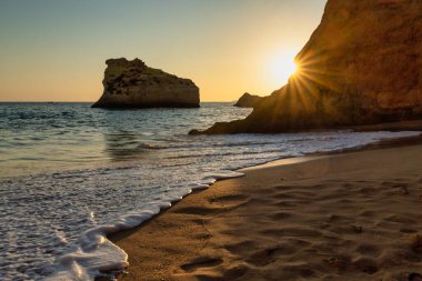 Kumsalda güneşin doğuşunu, kumdaki yumuşak bir dalganın köpüğüyle izlemek.