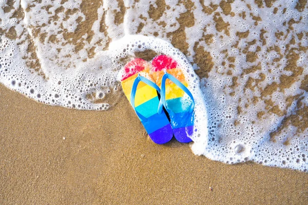 colorful slippers on the beach on a summer day - gay pride flag - flip flop