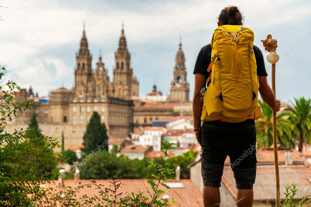 pilgrim looking at the cathedral of Santiago de Compostela in Spaink, backpack on his bac