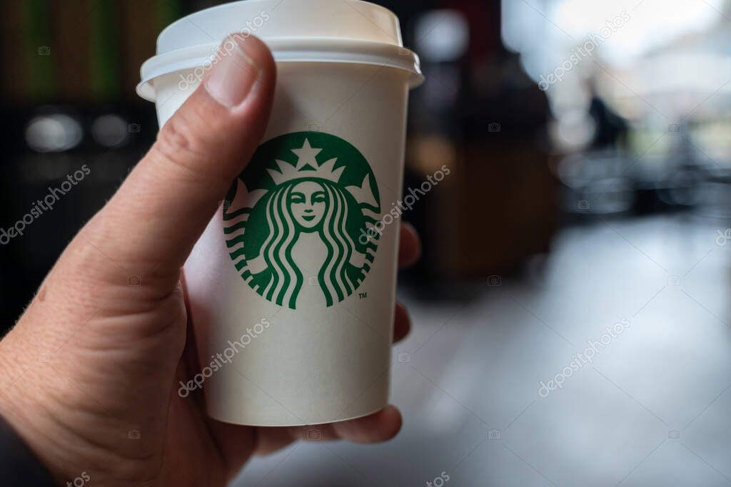 Man hand holding a Starbucks coffee cup