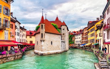 People walk near the Thiou canal in Old Town of Annecy in France, encircling the medieval palace, Palais de l'Isle - Travel concept