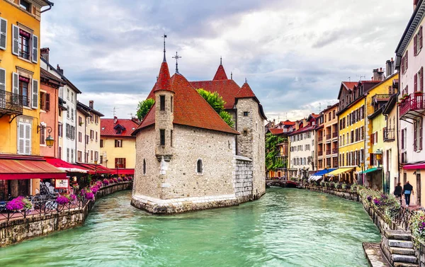 People walk near the Thiou canal in Old Town of Annecy in France, encircling the medieval palace, Palais de l'Isle - Travel concept