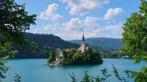 Bled Gölü 'ndeki bir adadaki Katolik kilisesinin manzarası. Dağlar ve arka planda Sloven Alpleri' nin köyleri var.