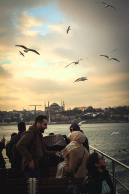 İstanbul, Türkiye, 2 Ocak 2022 - Halk toplu taşıma feribotuna binerken güvercinleri besliyor
