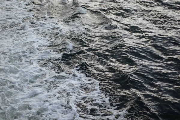 Small waves breaking in the ocean from ship passing through
