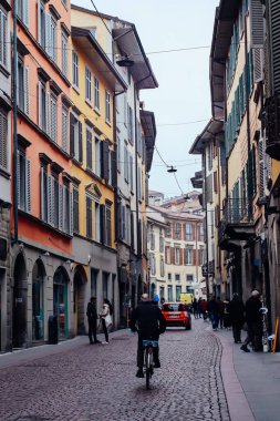 Bergamo, İtalya, 30 Mart 2022 - Apartman binaları, mimarisi ve bisikletli bir adam olan Paved Yolu