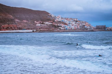 Okyanusun dalgalarında sörf yapan bir sörfçü.
