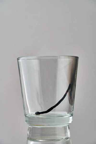 The remains of a burnt match lie in a transparent glass — Stock Photo, Image