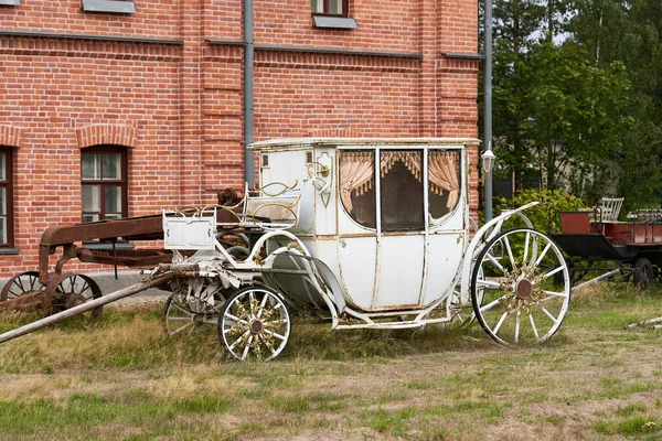 Old white carriage on the background of a red brick building — Stock Photo, Image