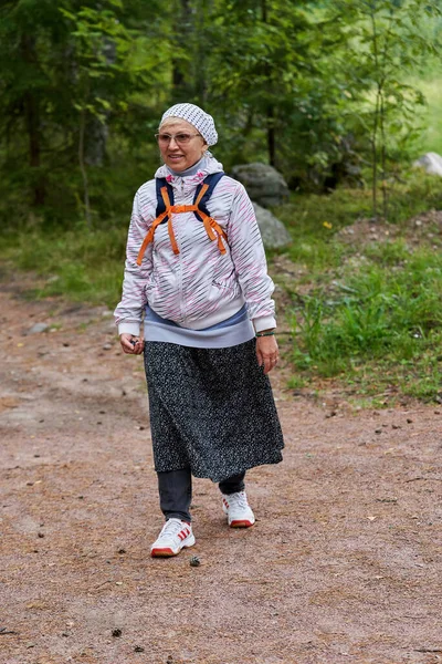 Una mujer vestida de peregrino religioso camina por un camino forestal — Foto de Stock