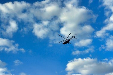 Bulutların ve mavi gökyüzünün üzerinde uçan helikopter