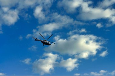 Bulutların ve mavi gökyüzünün üzerinde uçan helikopter