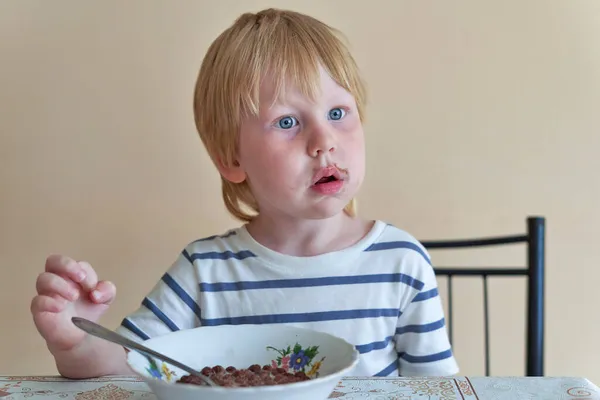 Мальчик завтракает с шоколадными шариками с молоком — стоковое фото
