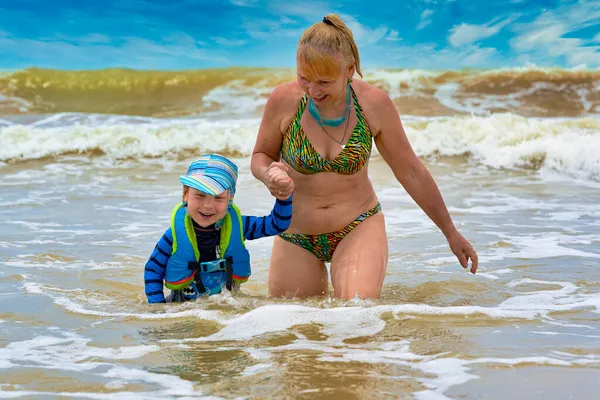 Женщина берет ребенка в спасательном жилете из бурного моря — стоковое фото