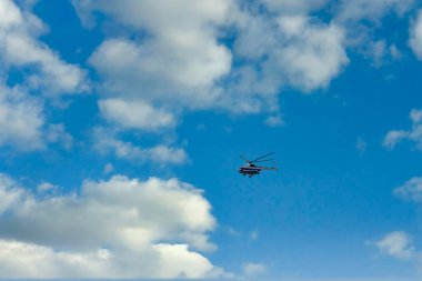 Bulutların ve mavi gökyüzünün üzerinde uçan helikopter