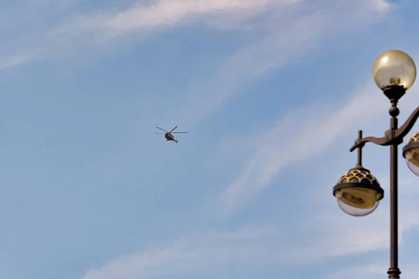 Летящий вертолет на фоне голубого неба с еловыми облаками — стоковое фото