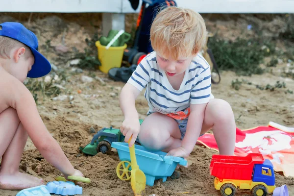 Двое детей играют в песке с пластиковыми игрушками — стоковое фото
