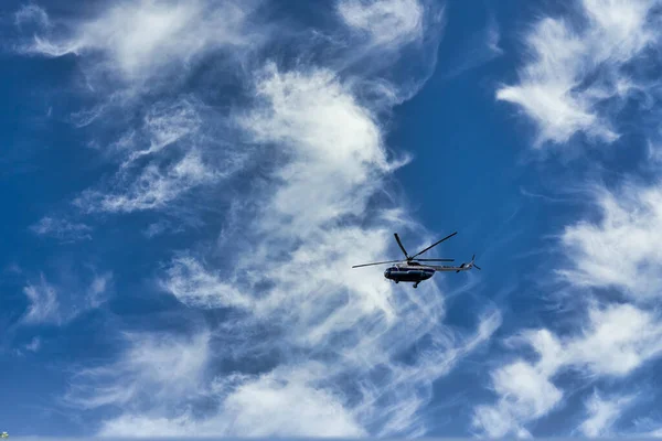 Летящий вертолет на фоне облаков и голубого неба — стоковое фото