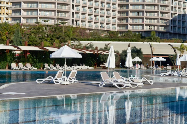Бассейн с голубой водой, шезлонги и зонтики на заднем плане отеля — стоковое фото