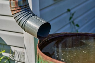 Kanalizasyon borusu paslı demir fıçıya yağmur suyuyla bağlanmış.