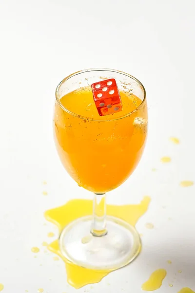 Un dado che cade in un bicchiere di liquido arancione ha causato una spruzzata — Foto Stock