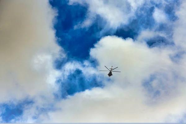 Hubschrauber fliegen vor dem Hintergrund von Wolken und blauem Himmel — Stockfoto
