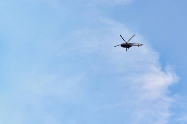 Uçan helikopter, ladin bulutlu mavi gökyüzünün arka planında
