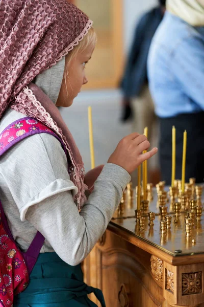 Um jovem paroquiano acende uma vela no altar da igreja — Fotografia de Stock