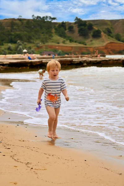 海岸沿いの砂浜に男の子が走っている。 — ストック写真