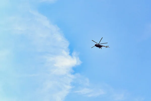 Летящий вертолет на фоне голубого неба с еловыми облаками — стоковое фото