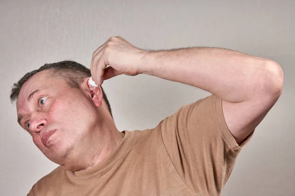 Um homem infunde remédio em seu ouvido com uma pequena pipeta de uma garrafa de farmácia. — Fotografia de Stock