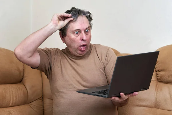 데 바니 (Devani) 에 앉아 있는 나이의 한 남자가 노트북으로 뉴스를 봅니다. — 스톡 사진