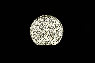 Siyah arka planda beyaz parlayan top, gece lambası karanlıkta parlıyor.