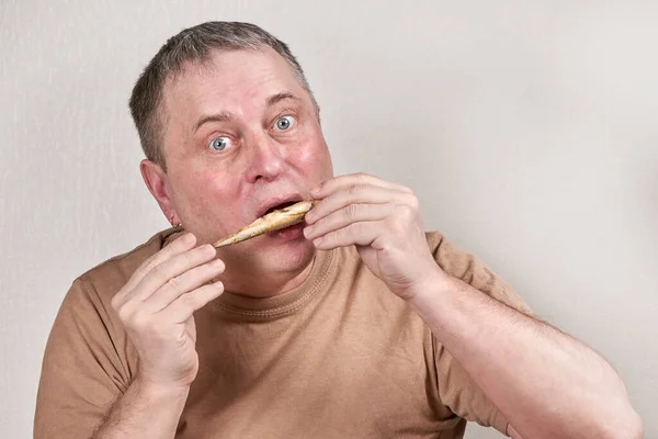 Homem comendo peixe cheiroso frito segurando peixe com as mãos na frente da cara — Fotografia de Stock