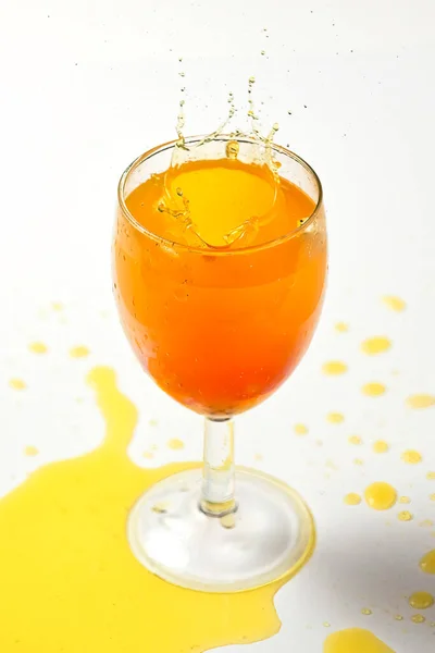 Всплеск апельсиновой жидкости в стакане из брошенных кубиков — стоковое фото