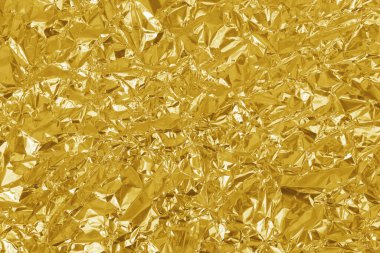 Altın folyo yaprağının parlak dokusu, arkaplan ve tasarım çalışmaları için soyut sarı ambalaj kağıdı.