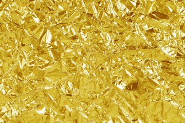 Altın folyo yaprağının parlak dokusu, arkaplan ve tasarım çalışmaları için soyut sarı ambalaj kağıdı.