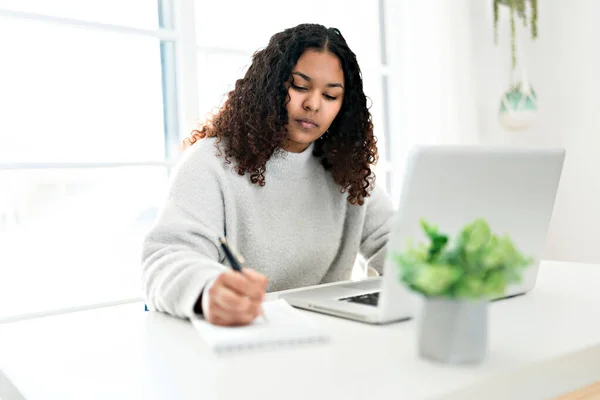 Ung afrikansk amerikansk kvinde arbejder på laptop hjemme kontor - Stock-foto