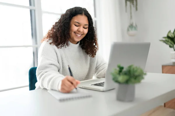 Ung afrikansk amerikansk kvinde arbejder på laptop hjemme kontor - Stock-foto