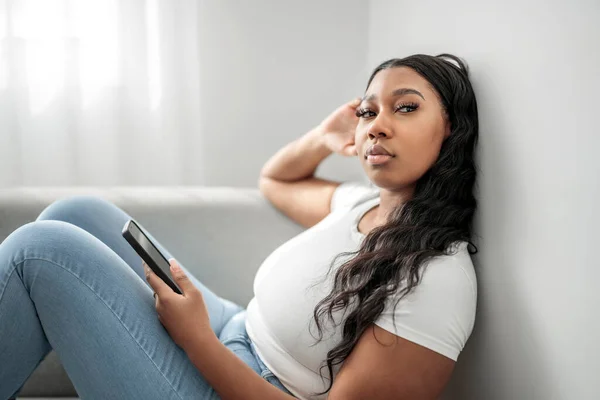 Attraktiv Ung Afrikansk Kvinna Sitter Soffan Hemma Med Mobiltelefon — Stockfoto