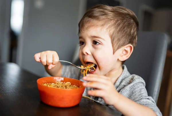 Kid eating spaghetti in the kitchen having fun — Photo