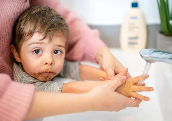 Mother washing kid hands after boy eat cake — Photo